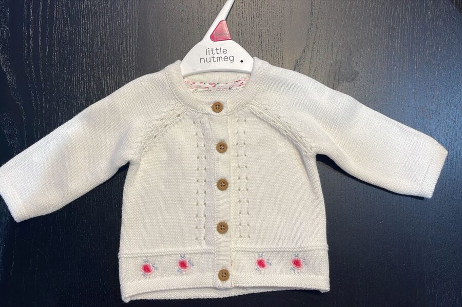 # balta adīta jaciņa ar pogām un sarkaniem ziediem apakšdaļā 50 cm