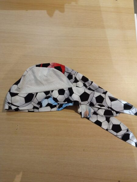 Plāna cepurīte pelēka ar futbola bumbām, ar baltu sietiņu augšā, sasienama aizmugure 44-48 izmērs